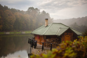 small cabin with chimney on lake in rainy weather