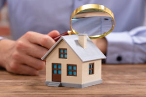 hand holding magnifying glass over house
